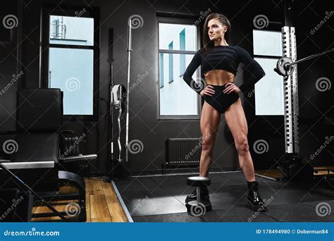sport girl doing squat for legs with iron barbell working hard for strong muscles alone in gym