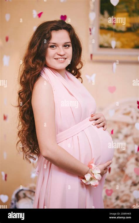 Young Beautiful Pregnant Woman With Long Red Hair In A Delicate Boudoir Pink Long Dress Fashion