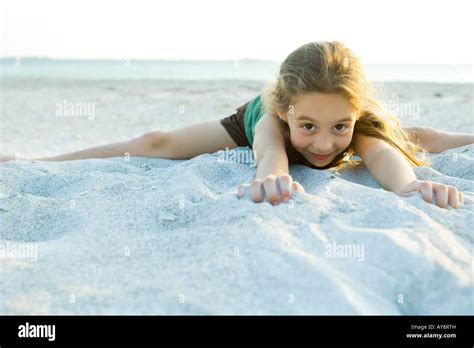 Little Girl Lying In Sand At The Beach Smiling At Camera Stock Photo