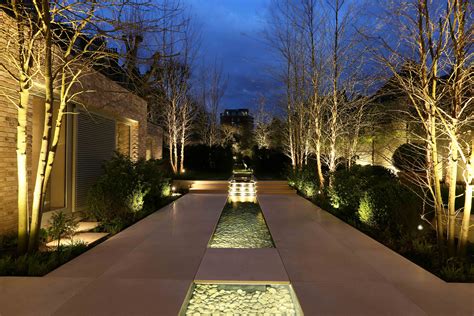 An Outdoor Walkway Lit Up At Night With Trees In The Background And