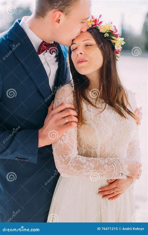 outdoor portrait of happy sensual wedding couple embracing handsome groom holding his pretty
