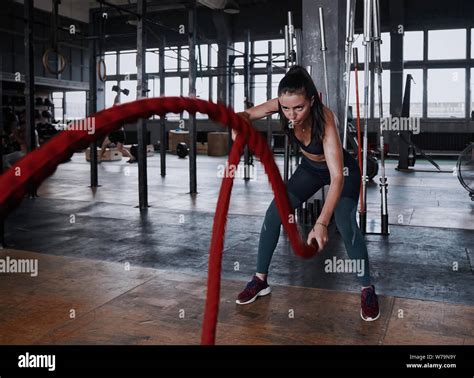 Fit Woman Using Battle Ropes During Strength Training At The Gym Athlete Moving The Ropes For