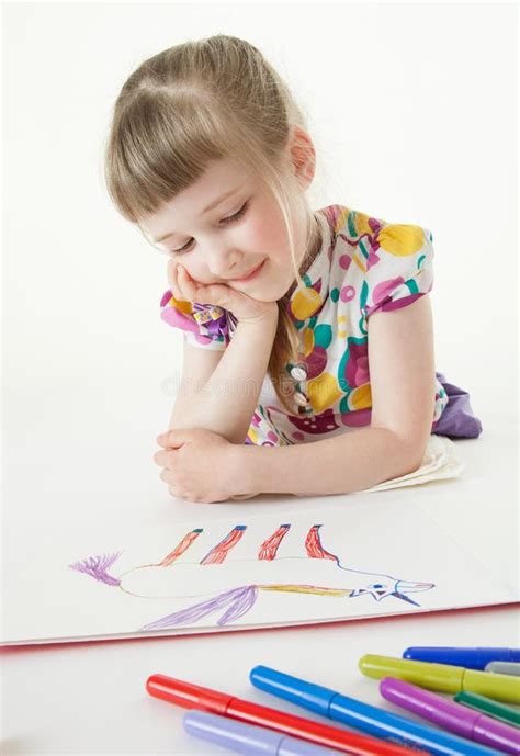 Pretty Little Girl Lying On The Floor And Looking On Her Drawing Stock