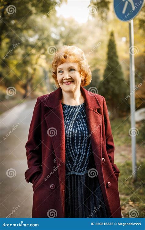 russian mature woman with short hair smiling looks to the side outdoors in autumn in an