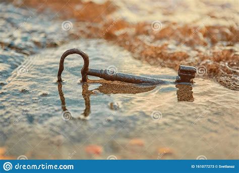 An Old Rusty Lost Treasure Key Lying In The Sand In The Surf On The