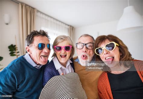Portrait Of Two Senior Couples Having Fun At A Party At Home High Res