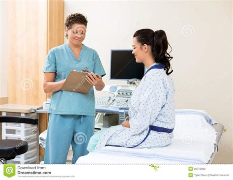Nurse Writing Notes With Patient Sitting On Bed Stock