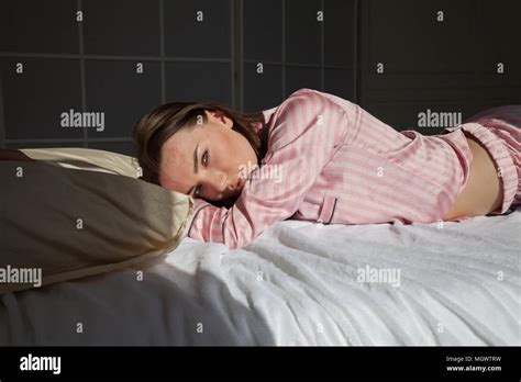 Brunette Woman In Pink Pajamas Lying On Bed Stock Photo Alamy