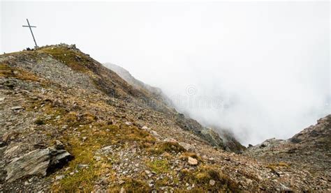 Cliff With Cross Above Clouds In Mountains Of Austria Stock Photo