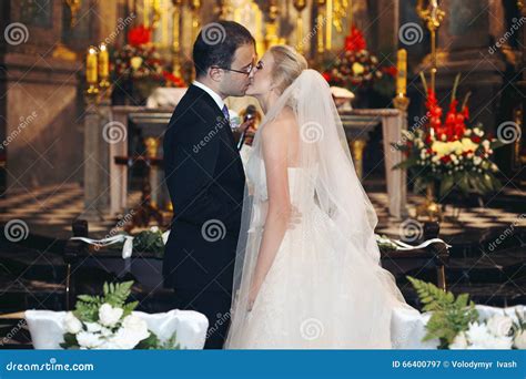 Newlywed Bride And Groom First Kiss At Wedding Ceremony In Church Stock