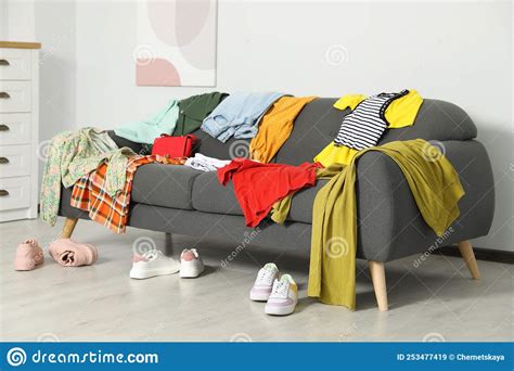 Messy Pile Of Clothes On Sofa And Shoes In Living Room Stock Image