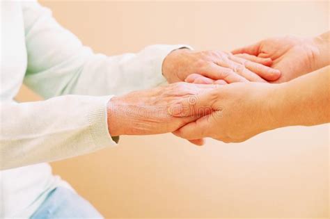 Close Up Of Senior Woman And Young Woman Holding Hands Care And