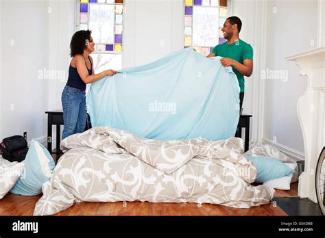 Couple Changing Sheets On Bed Stock Photo Alamy