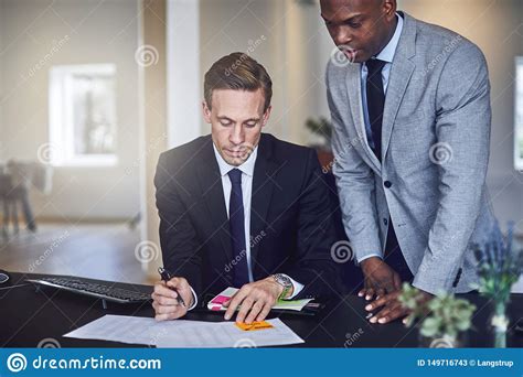 Two Businessmen Going Over Paperwork Together In An Office Stock Image