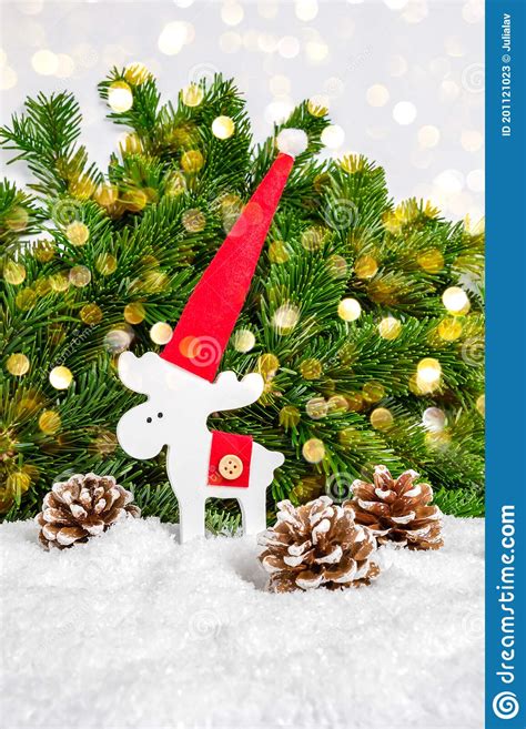 White Christmas Reindeer In Red Santa Hat And Pine Cones In Snow With