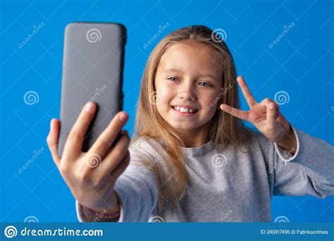 Portrait Of An Excited Little Girl Taking A Selfie Over Blue Background