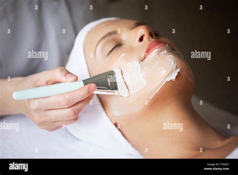 Female Therapist Applying Facial Mask On Womans Face In Spa Stock