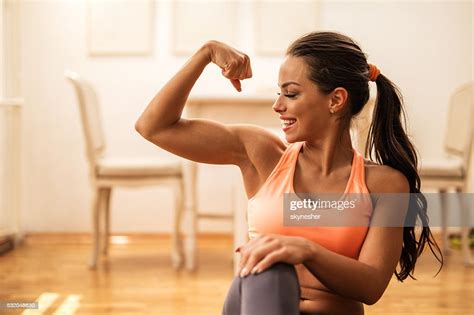 Sportive Heureuse Femme En Fléchissant Ses Biceps Comme À La Maison