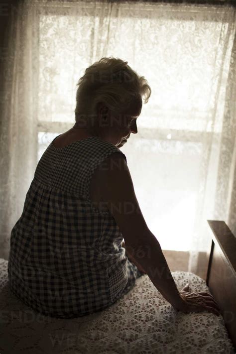 Pensive Older Woman Sitting On Bed Stockphoto