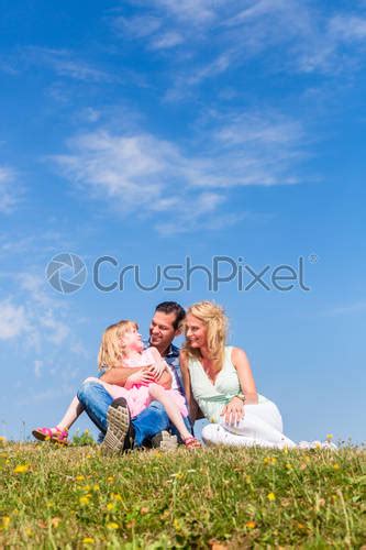 Girl On Dads Lap Sitting On Meadow Or In Field Stock Photo