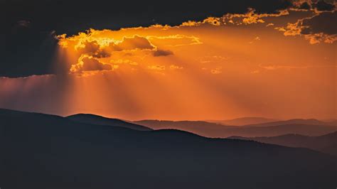 Download Wallpaper 1366x768 Mountains Sunset Clouds Rays Dusk