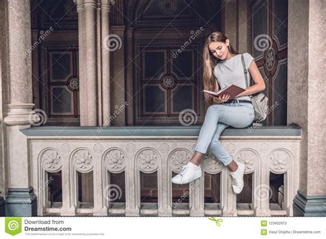 Beautiful And Confident Young Female Student Sitting On The Railing In