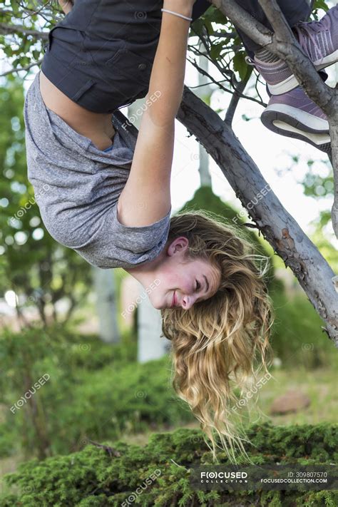 Blonde Teenage Girl Hanging Upside Down From Tree Summer People