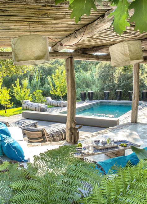 An Outdoor Living Area With Couches And Tables Next To A Pool Surrounded By Greenery