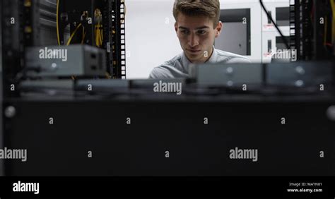 Technician Performing Maintenance Tasks In A Server Room Rack Stock