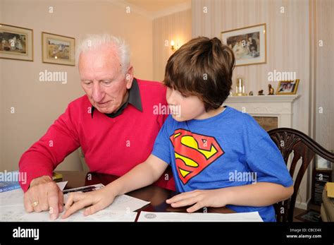 Grandad And His Ten Year Old Grandson Sit At A Dining Table In A Neat