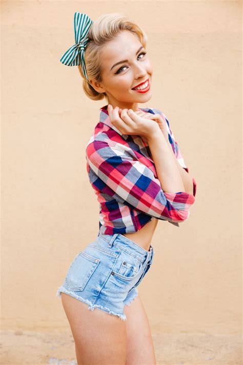Cheerful Cute Pinup Girl In Plaid Shirt Standing And Smiling Over Pink