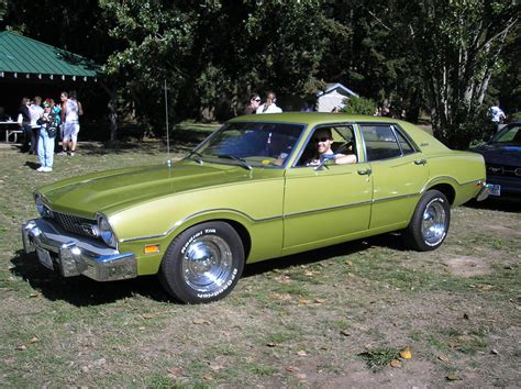 An Old Green Car Parked On Top Of A Grass Covered Field