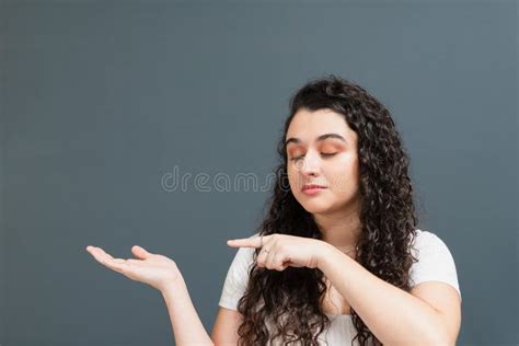 Cheerful Young Woman Pointing Her Finger At Her Palm Stock Photo