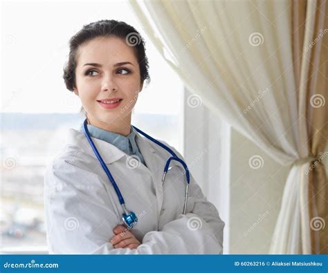 Portrait Of Young Woman Doctor On White Coat Standing Near Window Stock