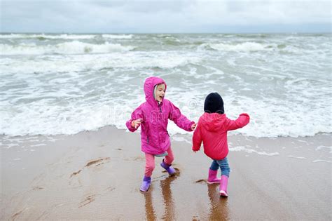 Two Little Sisters Having Fun On A Sandy Beach Of Baltic Sea Stock