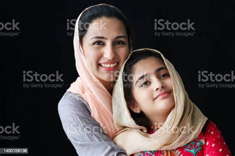 portrait of adorable smiling pakistani muslim girl with beautiful eyes and her mother wearing