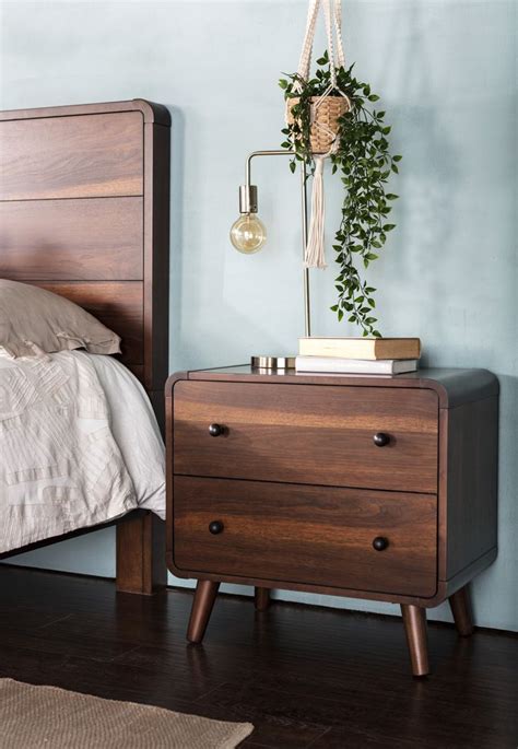 A Bedroom With A Bed Nightstand And Potted Plant On The End Table Next