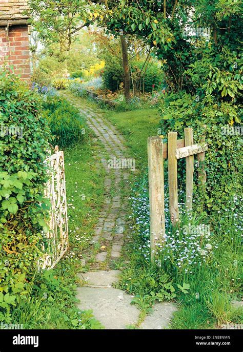 Cobbled Pathway Leading Through Open Wooden Gate Into Garden Stock