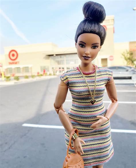 a barbie doll is holding a purse and wearing a striped dress in the parking lot