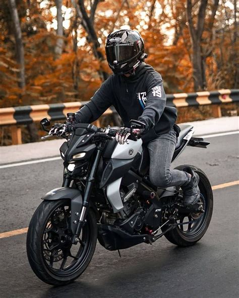 A Man Riding On The Back Of A Silver Motorcycle Down A Curvy Road