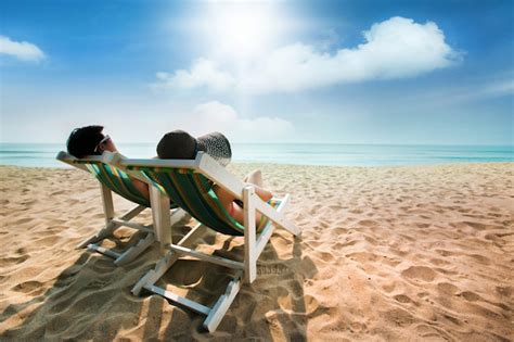 Pareja Tomando El Sol En Una Silla De Playa Y Una Sombrilla Foto Premium