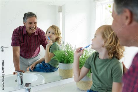 Smiling Caucasian Grandfather In Bathroom With Grandson Brushing Teeth