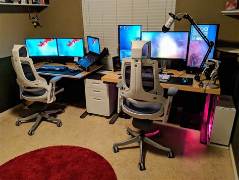 Three Computer Monitors Sitting On Top Of Desks In Front Of A Red Round Rug