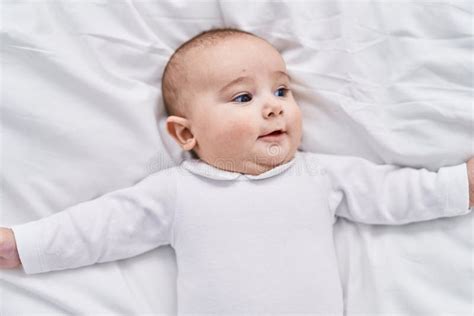 Adorable Baby Smiling Confident Lying On Bed At Bedroom Stock Photo
