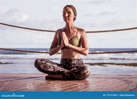 joven atractiva sentada en el suelo de madera practicando yoga y pranayama lotus pose