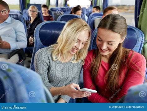 Giovani Donne Felici In Bus Di Viaggio Con Lo Smartphone Immagine Stock