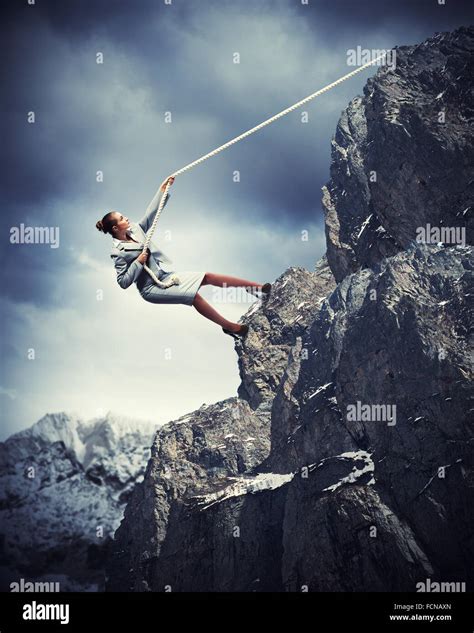 Businesswoman Climbing Steep Mountain Hanging On Rope Stock Photo Alamy