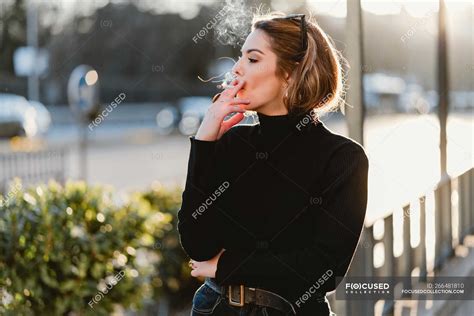 Pretty Woman Smoking Cigarette On Sunny Street — Looking Away