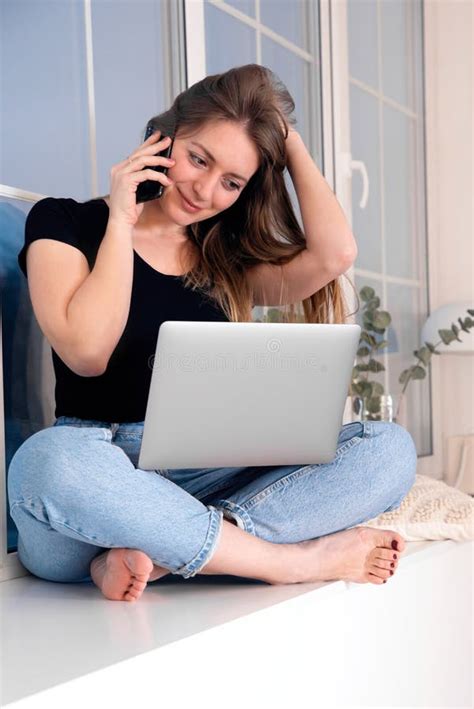 Girl Sitting With Crossed Legs And Working On Laptop Stock Photo