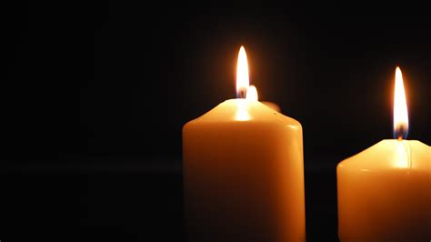 Three Candles Burn With A Soft Yellow Flame In The Dark And Are